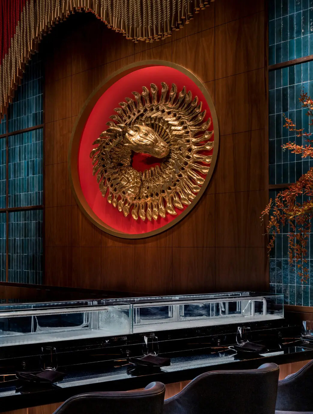Full buyout space. Striking golden dragon head sculpture set in a red circular frame on a wood-paneled wall at Gekko —