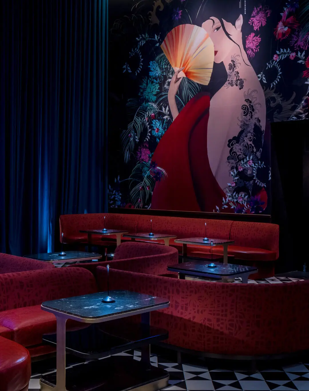 Gekko Lounge Room featuring deep red booths, black marble tables, and dramatic wall art of a woman in a red dress—perfect for intimate gatherings or private events.