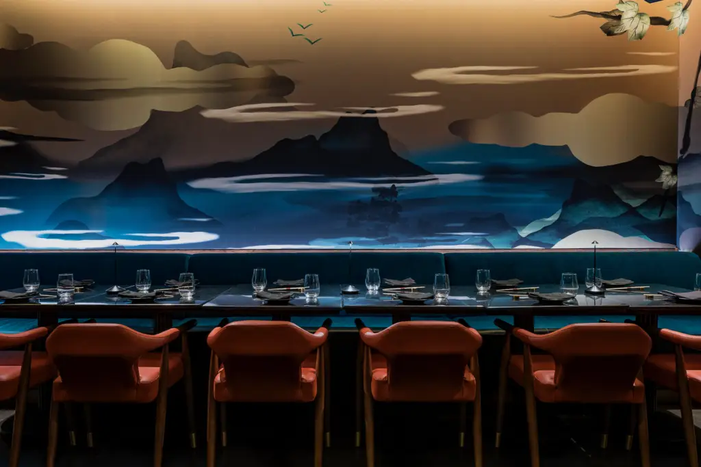Elegant private dining room at Gekko, featuring a moody landscape mural, teal banquette seating, coral chairs, and a sleek table set with modern glassware and chopsticks.